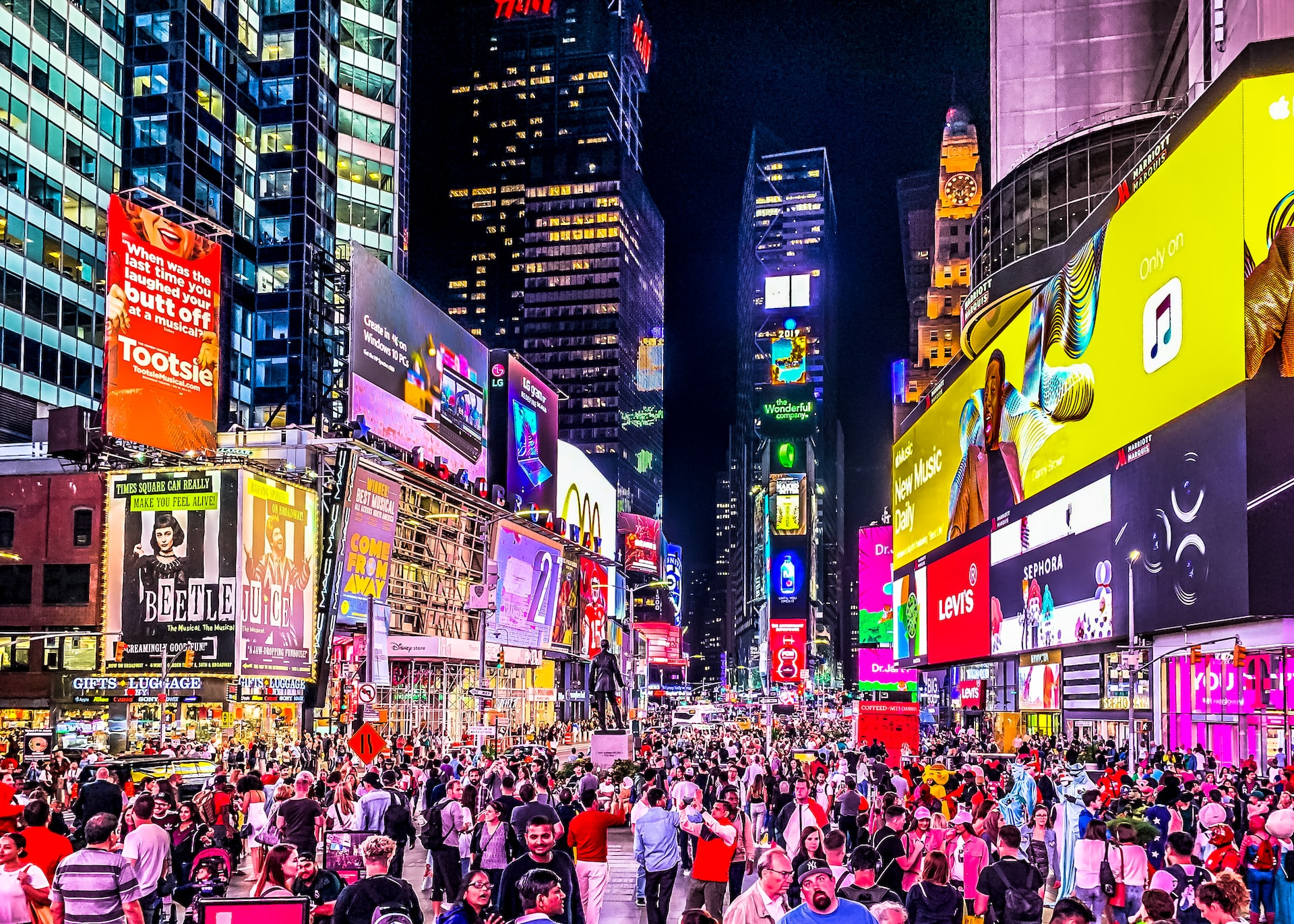 The New York Times Square at night teeming with people and illuminated billboard signs