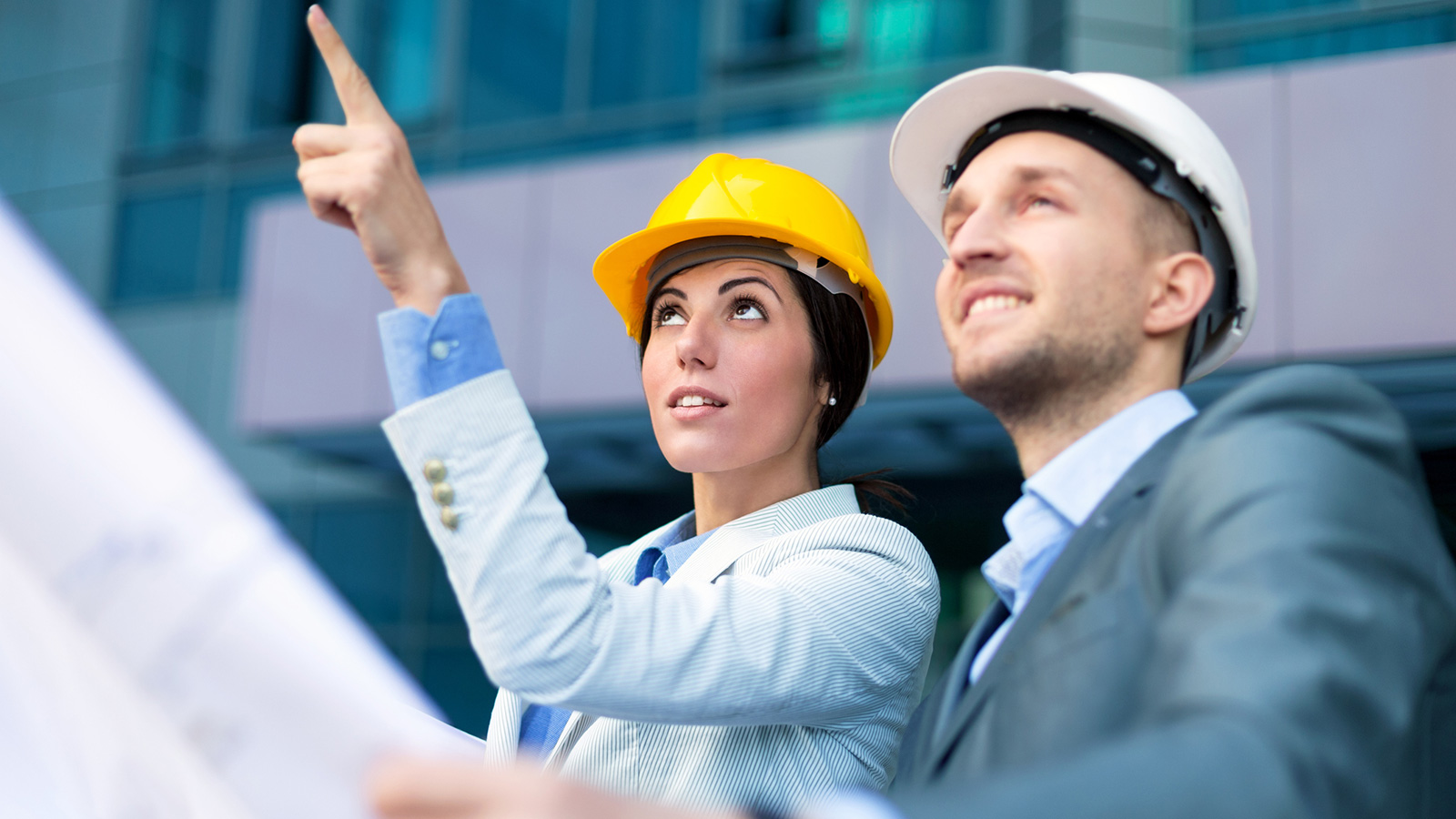 A man and woman wearing a construction hat while looking up