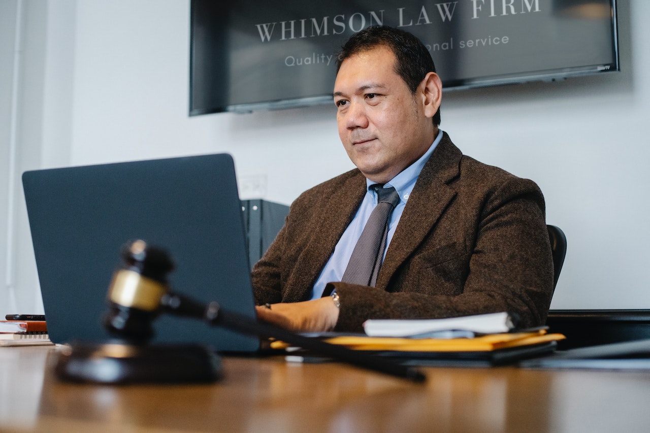 Positive Asian lawyer using laptop in modern office